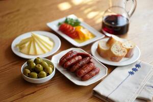 A table with a plate of food, a glass of wine and a bowl of olives photo