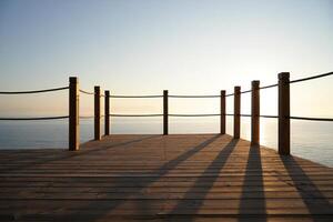 Beach Background Serene Ocean View Sunrise on Wooden Deck with Rope Railing photo