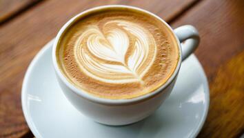 Coffee Background Aromatic Latte Coffee with Heart Design Close Up View in White Cup on Wooden Table photo