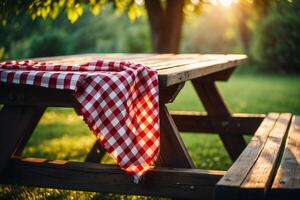 Nature Background Rustic Wooden Picnic Table Outdoors with Red Gingham Tablecloth at Sunset photo