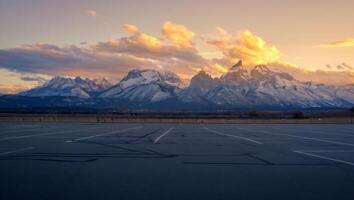 Nature Background Majestic Sunset Over Snowy Mountain Range Viewed From Empty Parking Lot photo
