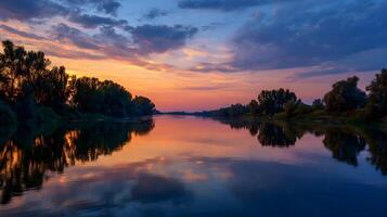 Tranquil sunset reflects on the water surface of a serene river surrounded by lush trees photo