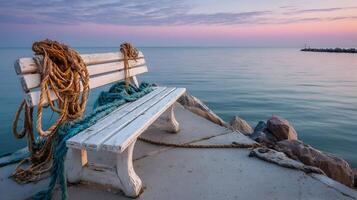 Seaside serenity an old white bench adorned with fishing nets rests by the tranquil ocean waters photo