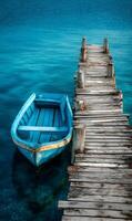 A serene turquoise sea meets a weathered wooden dock with a small blue boat gently resting nearby photo