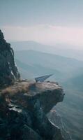 Paper airplane poised for flight on a majestic mountain cliff symbolizing dreams and aspirations against breathtaking scenery photo