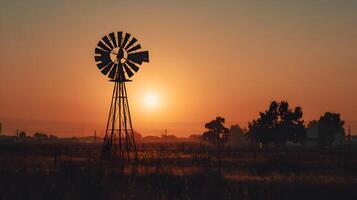 Windmill silhouetted against a vibrant sunset in a rural setting providing a scenic landscape view photo
