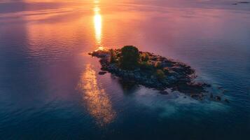 Serene island vista at sunset reflecting sunlight on water surface with rocky shore and foliage photo