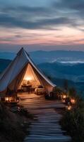 Idyllic mountain getaway camping tent illuminating the dusk with a stunning landscape view photo