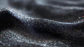 Abstract texture displaying undulating waves of glimmering dark metallic sand with iridescent sparkles photo