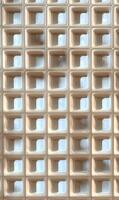 Repetitive geometric square pattern forming an abstract wall facade with light and shadow interplay creating depth photo