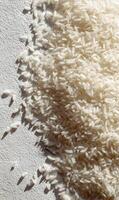 Overhead view of grains of rice scattered on a textured surface creating an abstract pattern in sunlight photo