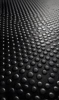 Monochrome textured surface with raised circular dots creating depth and dimension in dark tone rendering an abstract pattern for backdrops photo