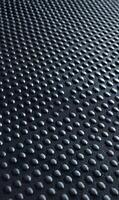 Abstract textured surface with evenly spaced circular bumps creating a rhythmic pattern in muted black tones photo