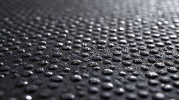 Close up photograph featuring water droplets on a dark textured surface creating an abstract look photo