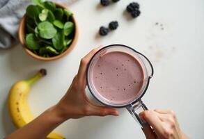A person holding a blender with a smoothie in front of a bowl of berries photo