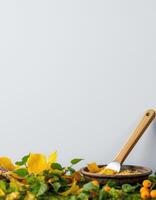 Yellow leaves and orange fruit with wooden bowl and spoon on green grass photo