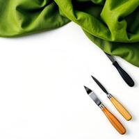 Green cloth with three kitchen knives on white background photo