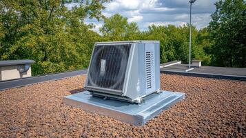Rooftop HVAC Unit Central Air Conditioning on a Flat GravelCovered Roof with Green Tree Background photo