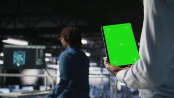 Data center worker using green screen mockup tablet, doing maintenance on rigs handling AI tasks. Server hub admin using chroma key device to manage storage arrays supporting deep learning, camera A video