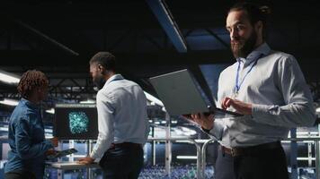 Data center admins monitoring artificial intelligence LLM visualization. Teamworking server room employees cooperating, overseeing rigs powering deep learning processes, camera A video