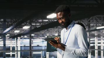 Admin on data center industrial platform analyzing infrastructure performance outputs on tablet. Server room employee doing job tasks, finetuning mainframes configurations, camera B video