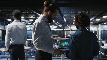 Server farm manager overseeing work done by engineer reviewing neural network code and LLM visualization dashboards. Team leader supervising worker monitoring AI system performance, camera A video