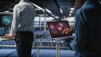 Technician in data center stressed by critical error popup on laptop during diagnostics session. Anxious IT specialist troubleshooting system fault affecting infrastructure performance, camera A video