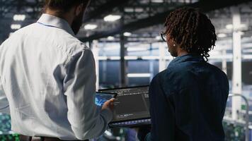 Data center system administrators performing maintenance on supercomputers used for AI. Engineering team managing server hub rigs used for deep learning training, camera B video