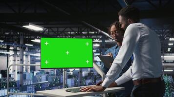Server room coworkers doing brainstorming, using chroma key device to review diagnostics. Employees doing maintenance tasks in data center, looking at isolated screen monitor, camera A video