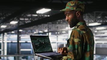 Soldier in server room uses geospatial data to support evacuation during emergency operations. Military data center personnel in uniform coordinating disaster response logistics using laptop, camera B video