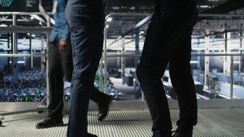 Data center team leader and worker reviewing performance dashboards of AI equipment rigs. Server room supervisor oversees programmer examining machine learning algorithms on screen, camera A video