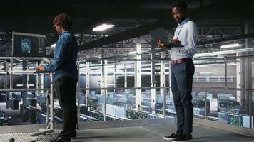 System administrators in data center using laptop to monitor neural network LLM visualization. Server hub teamworking colleagues overseeing rigs powering machine learning processes, camera A video