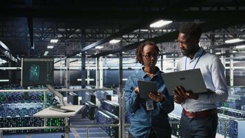 Data center admins running diagnostics on equipment using system monitoring tools to identify errors, doing brainstorming. IT experts work together to prevent failure and minimize downtime, camera A video