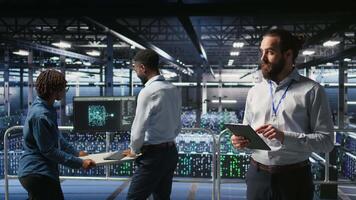 Technicians on data center platform using devices to monitor neural network LLM visualization. Industrial server hub engineering team overseeing rigs powering machine learning processes, camera A video