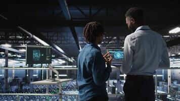 Data center engineering team doing maintenance on rigs handling AI processing tasks. Server hub teamworking colleagues managing storage arrays supporting deep learning training workflows, camera A video