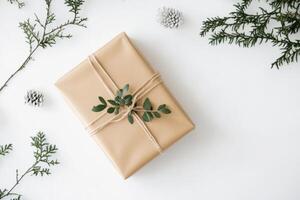 christmas gift wrapped in brown paper with green leaves on white background photo