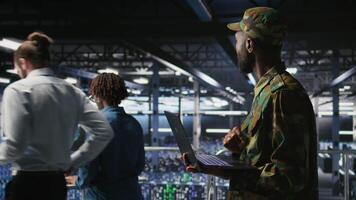 Army IT specialist in data center using laptop to defend networks against cyber threats. Military command center admin using notebook to identify potential intrusions or malicious activities, camera A video
