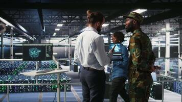 Army technicians in command center server room using artificial intelligence to detect cyber threats. Military data center experts use AI detection software to secure defense systems, camera A video