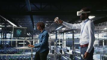 Engineer using VR headset in data center to update server tech, configuring equipment using software tools. Server hub employee reviewing hardware analytics using virtual reality, camera A video