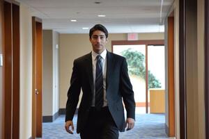 a man in a suit and tie walking down a hallway photo