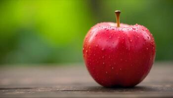 A closeup of a single ripe red apple with water droplets set on a wooden surface photo