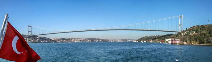 Bosphorus Bridge in Istanbul with Turkish flag on a clear day. photo