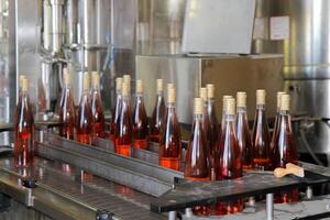 Bottles of rose wine on the production line of a winery. photo