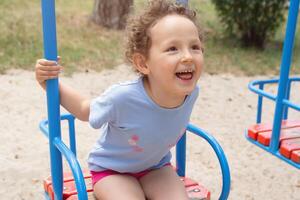 Curly child for swing in the summer park photo