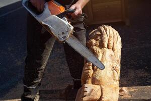 Man using chain saw to create wood carving. Industry photo