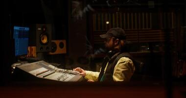A sound engineer sits in front of an audio mixer while recording a song in a recording studio photo