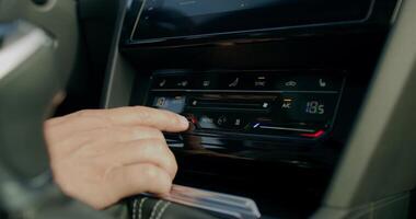 A man changes the settings of the air conditioner while driving a car. Close-up of his hands, an unrecognizable person. View from the car photo