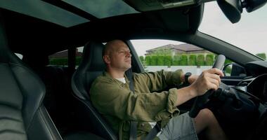 A man wearing a seat belt drives a car with a calm look. View from the car interior. Summer day photo