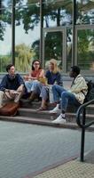 A group of young people are talking while repeating lessons sitting on the university steps. Sunny summer day photo