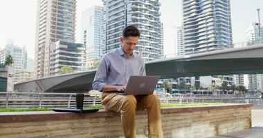 A serious man works remotely while sitting on a city street in a modern metropolis. photo